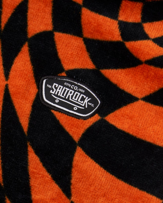 Close-up of a black and orange striped, ultra-absorbent towel with a "Warp Icon - Kids Changing Towel - Blue/Orange" branded label attached.