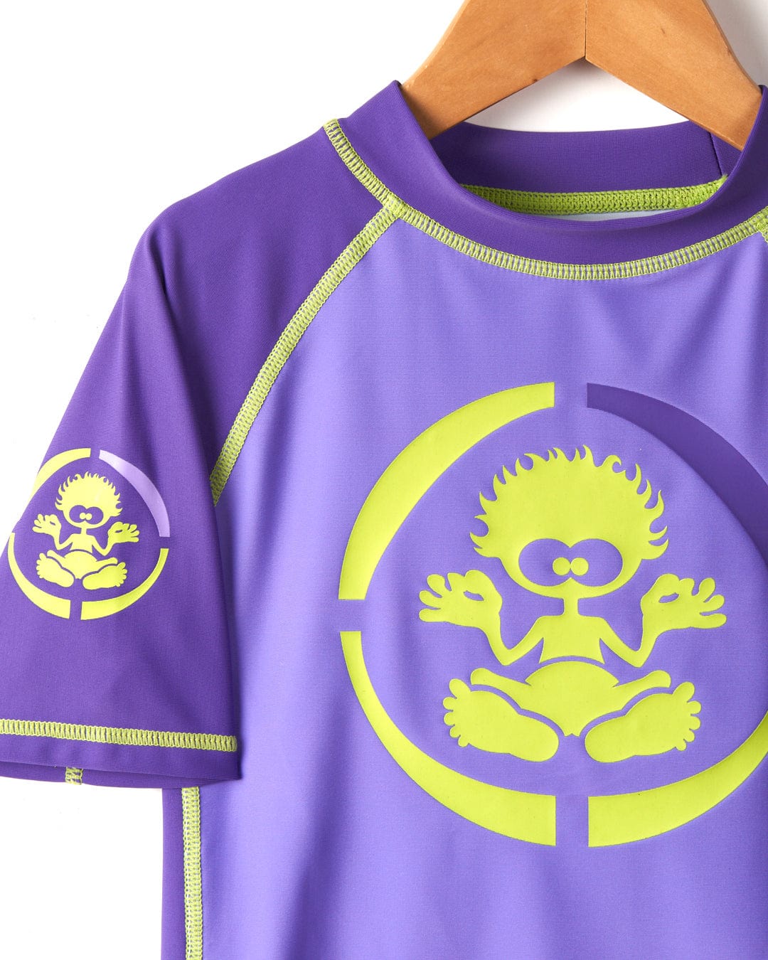 Purple Warp Icon - Recycled Kids Short Sleeve Rashvest by Saltrock with a neon yellow graphic of a cartoon character on a hanger against a white background, featuring UPF 50 protection.