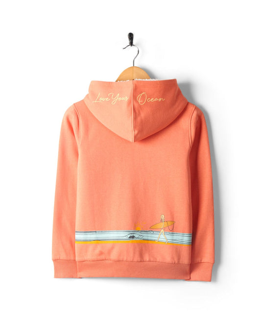 A Waveline - Kids Borg Lined Zip Hoodie in Coral by Saltrock, featuring an embroidered design of a person walking by a beach with the phrase "love your ocean" at the collar area. This hoodie is machine washable.