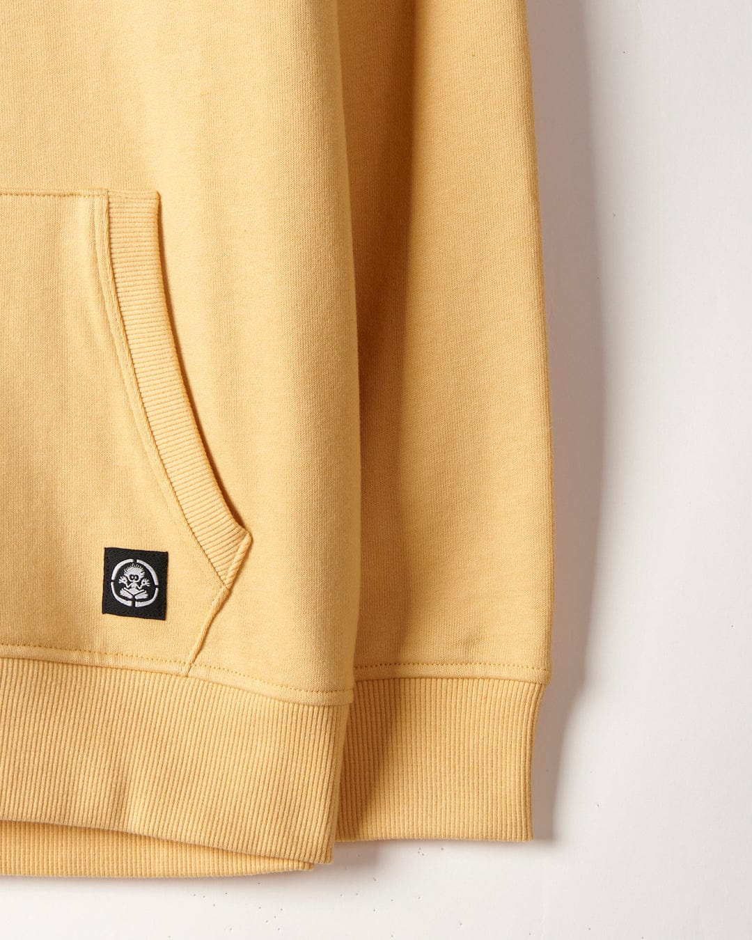Yellow Waveline - Kids Pop Hoodie detail showing sleeve and waist ribbing with a small Saltrock black logo patch on the kangaroo pocket.