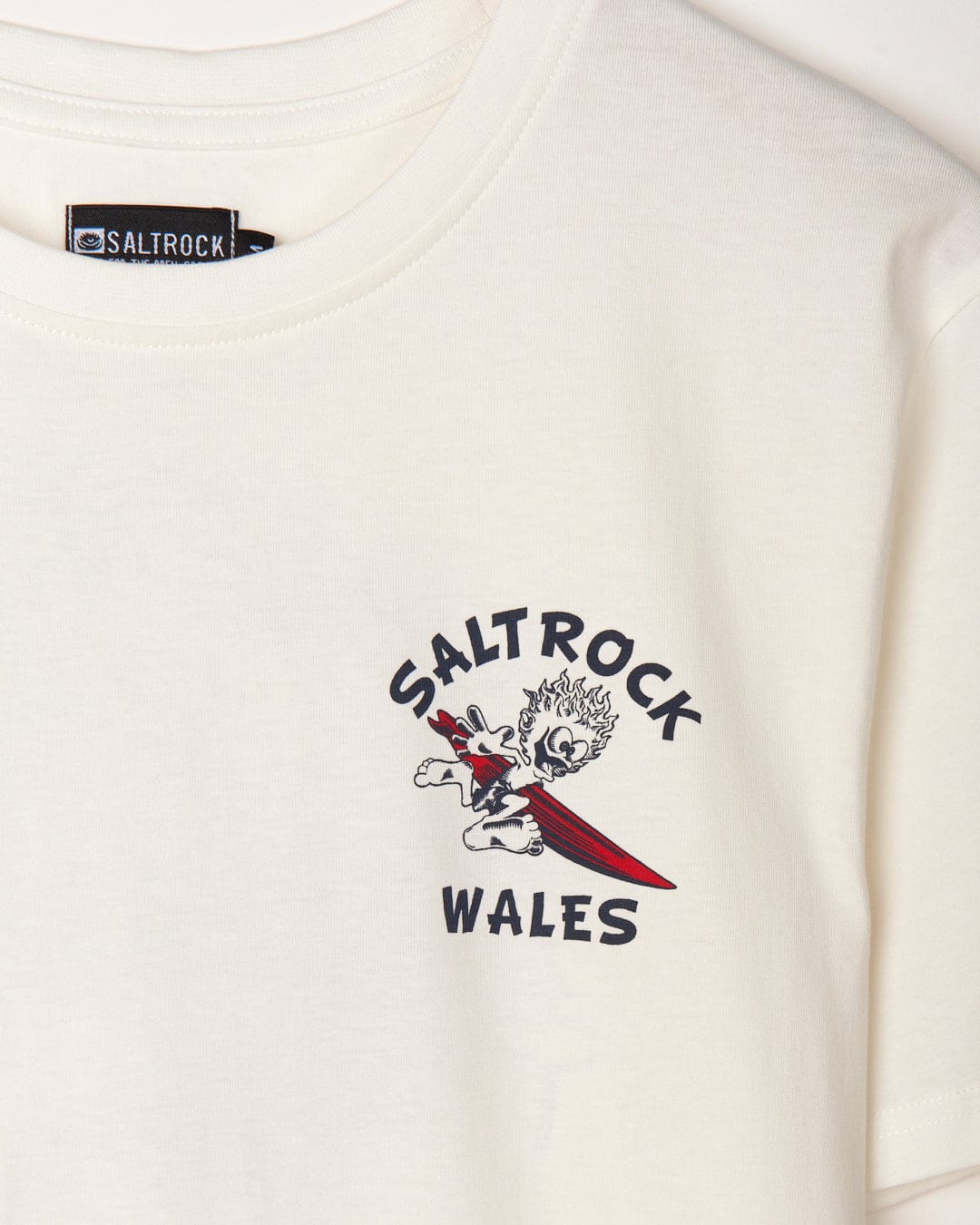 A white graphic t-shirt featuring the branding "Wave Rider Wales" by Saltrock.