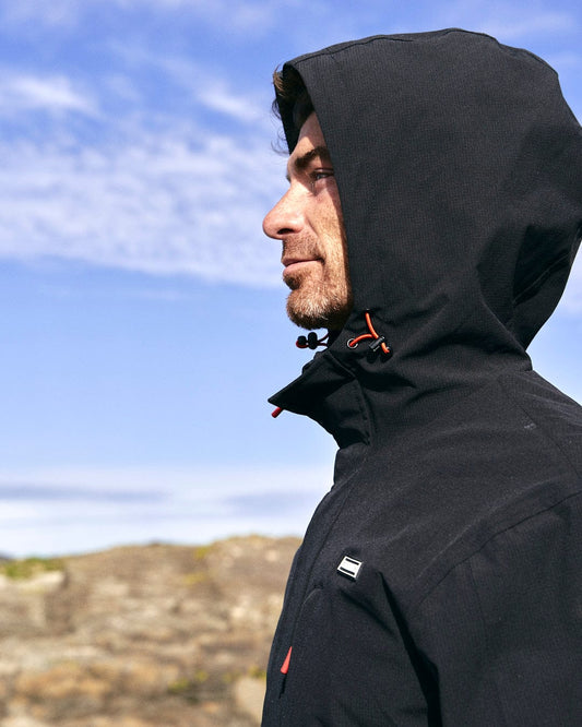 A man in a Saltrock Whistler - Mens Hooded Jacket - Black looking at the sky.