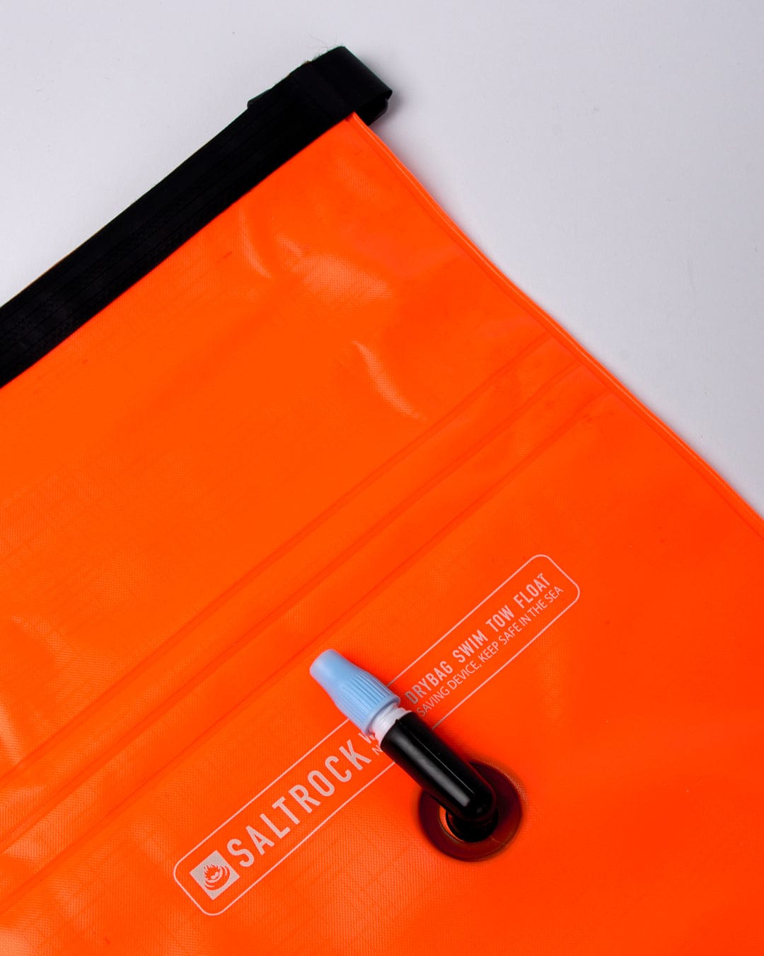 A bright orange Saltrock waterproof Wild dry bag with a blue sealing clip, ideal for cold water swimming.