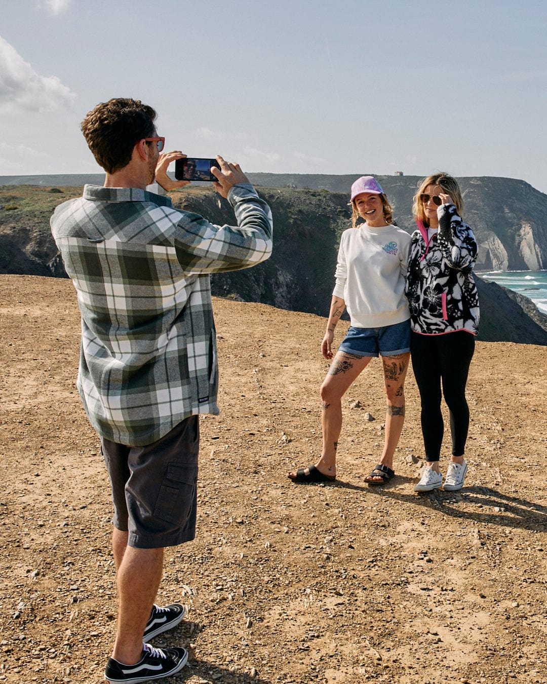 A group of people taking a picture of the ocean wearing Saltrock's Woody - Mens Borg Lined Shacket - Green Check with contrasting brown buttons on their clothes.