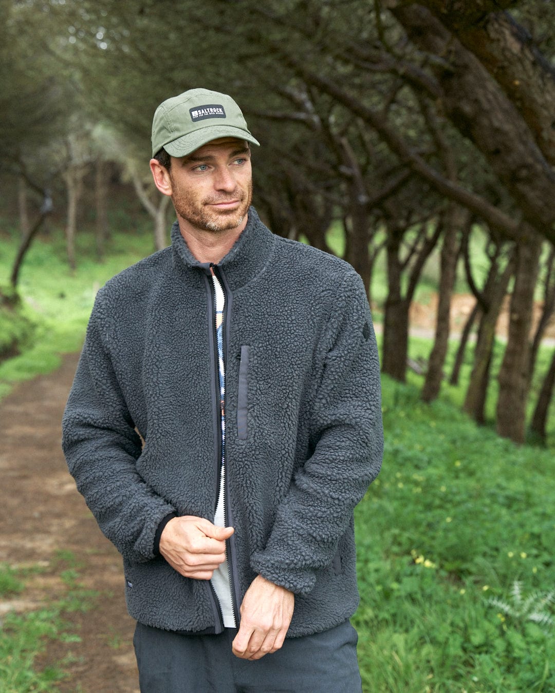 A man wearing a Saltrock hat and jacket with Saltrock branding standing on a path.