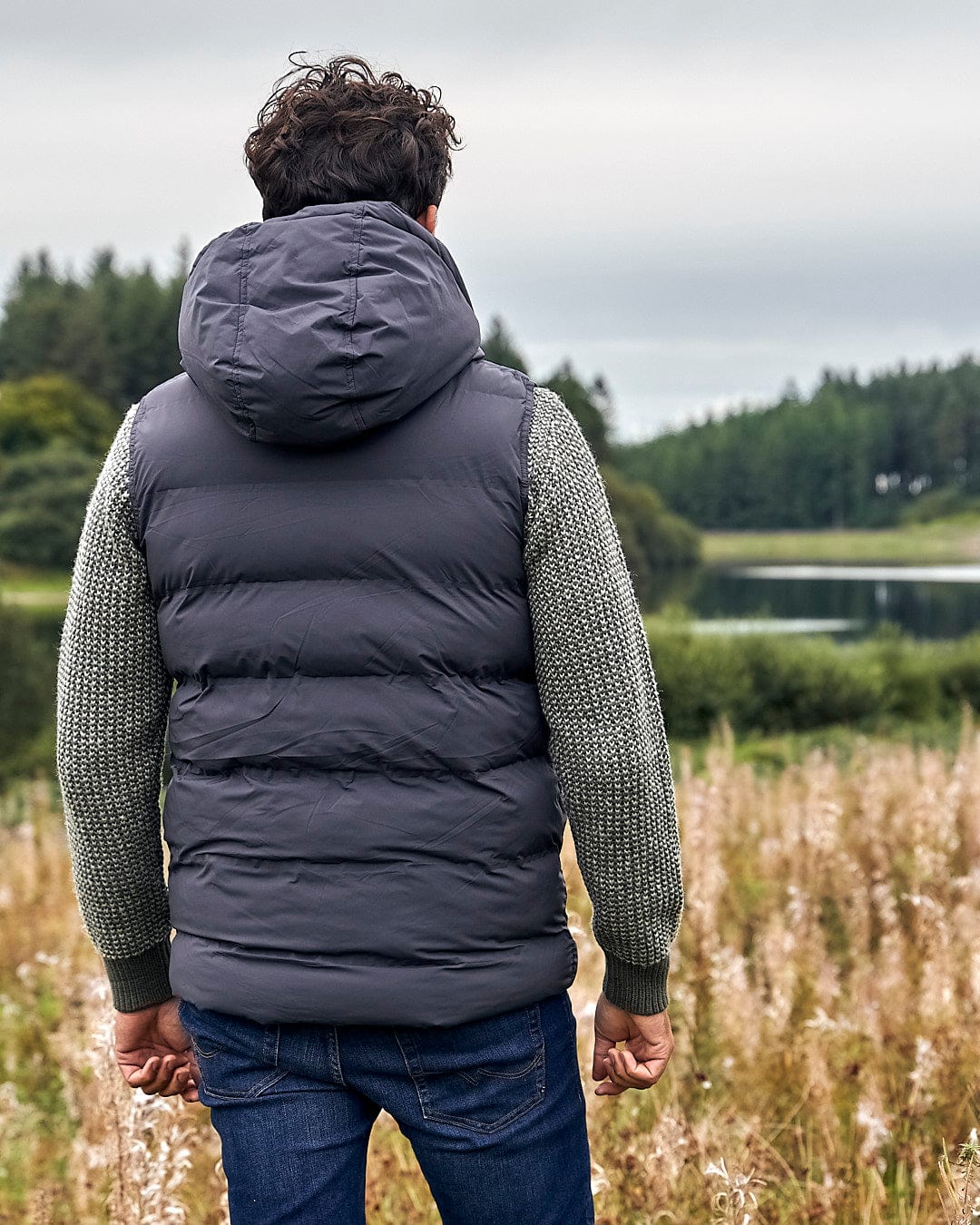 A man standing in a field with a Saltrock Xavier - Mens Padded Gilet - Dark Grey.