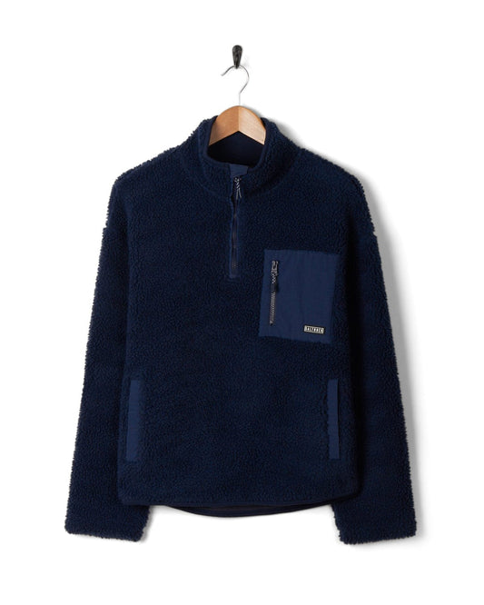 The Zella - Womens 1/4 Neck Fleece - Dark Blue, made of cosy fleece material, is hanging on a hanger.