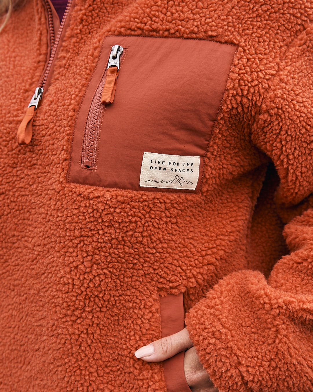 A woman wearing a Saltrock Zella Solid - Womens Borg Fleece - Burnt Orange jacket.