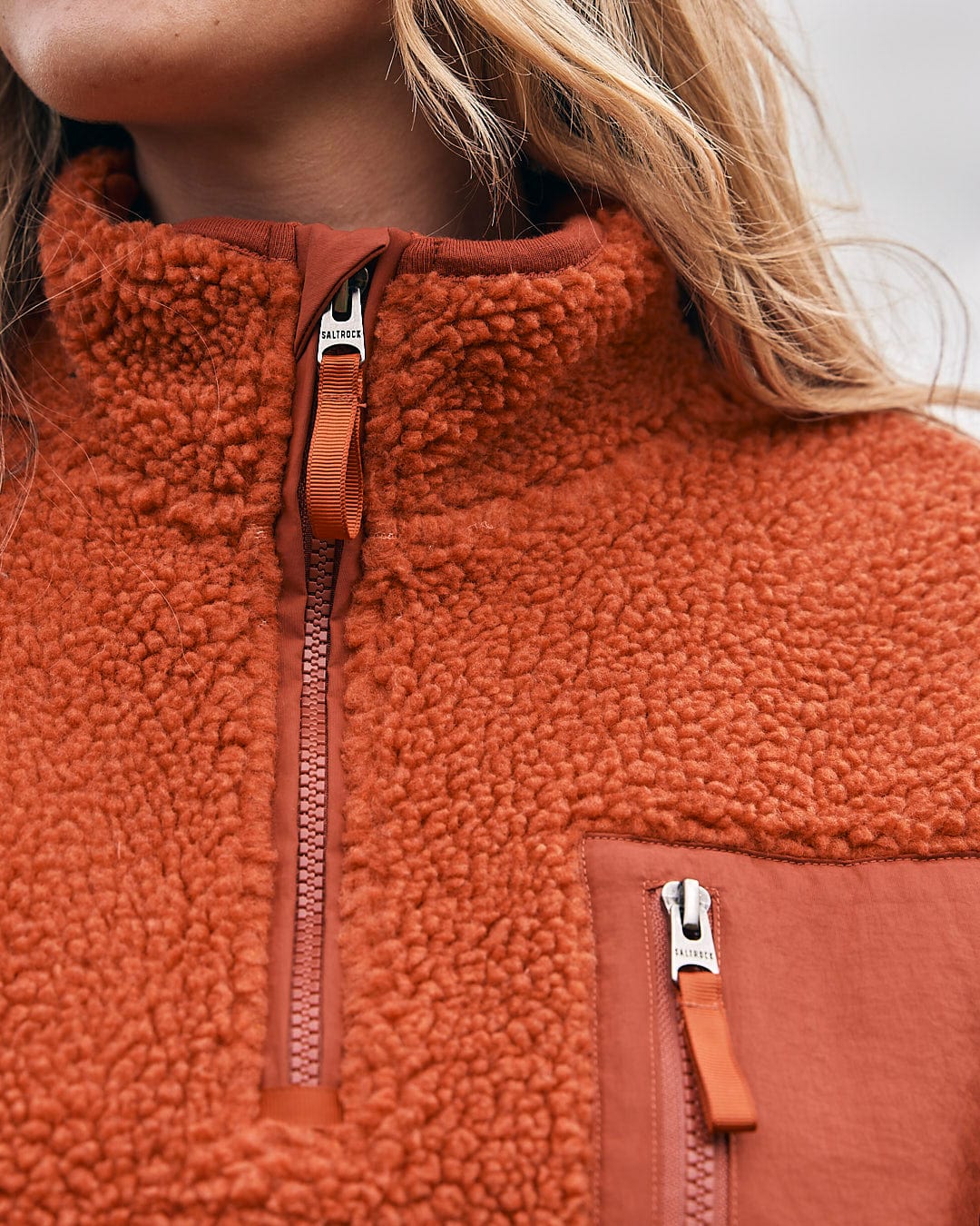 A woman wearing a Saltrock Zella Solid - Womens Borg Fleece - Burnt Orange jacket.