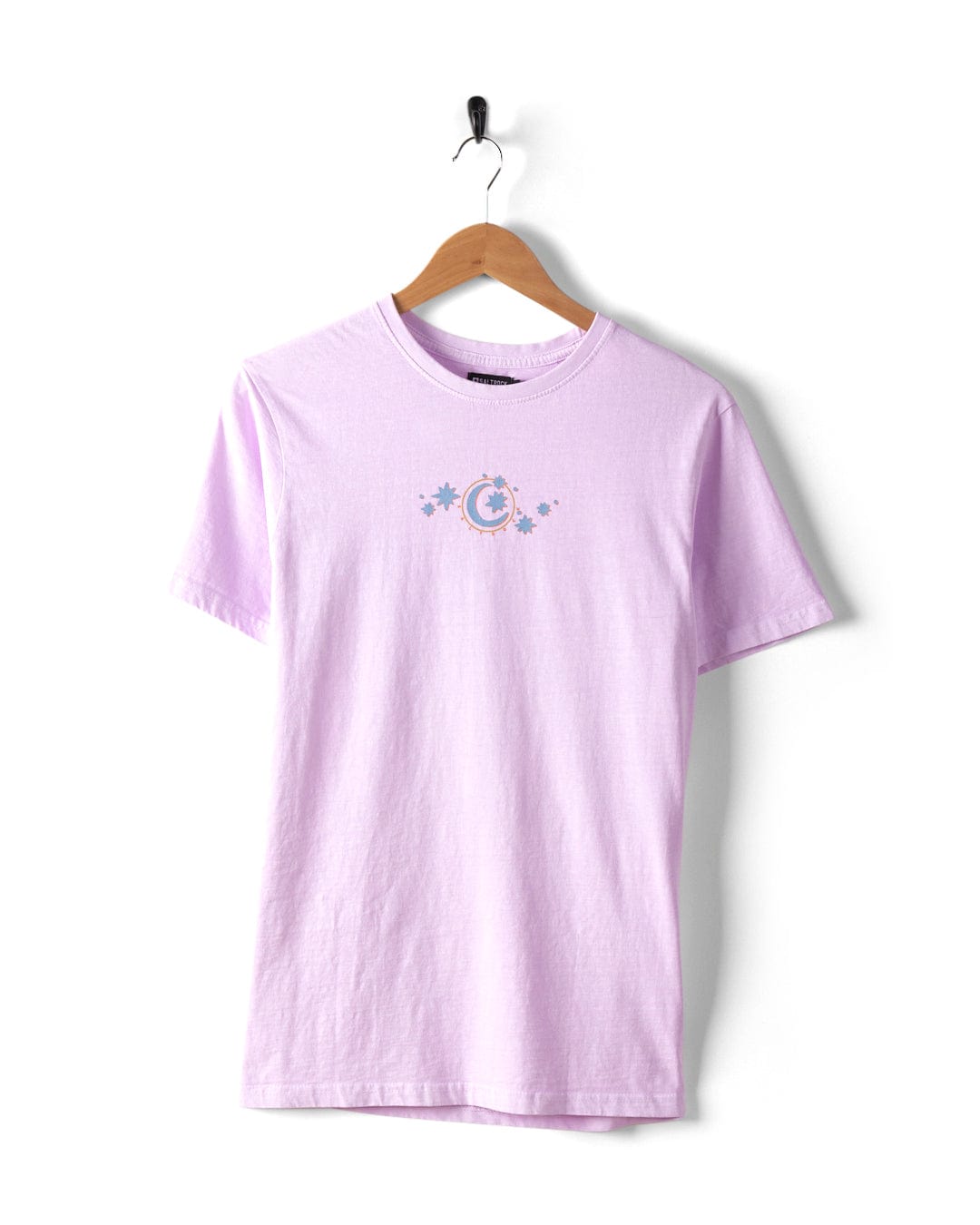The Better Days Women's T-Shirt from Saltrock, made with 100% cotton and designed in a crew fit style, drapes elegantly on a hanger. It is adorned with subtle Saltrock graphics, including a small floral and crescent moon design on the front.