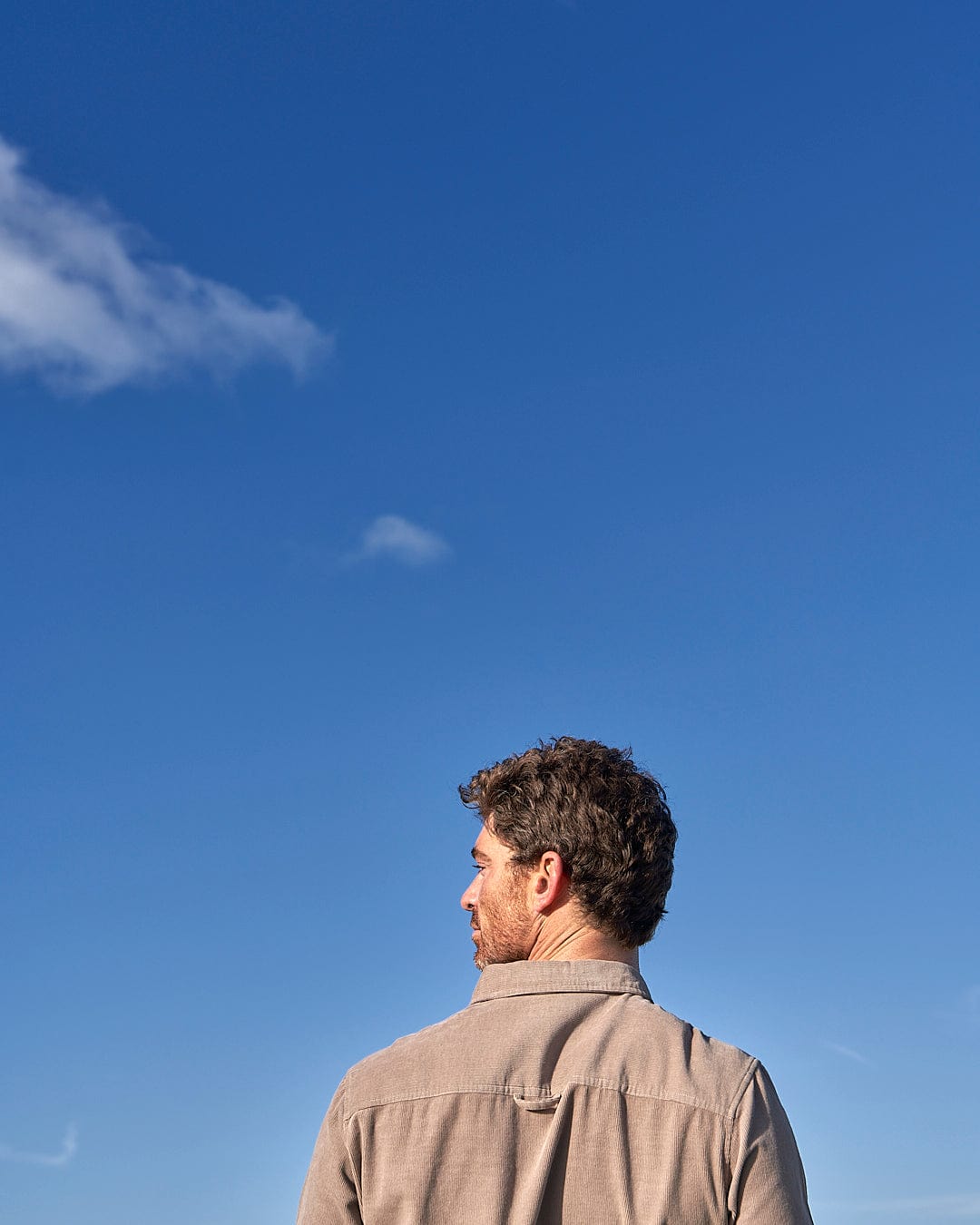 A man is flying a Saltrock - Ace Men Corduroy Shirt - Light Brown in a field.
