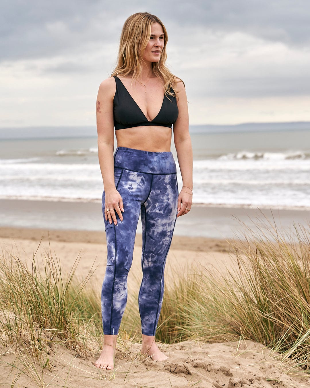 A woman in a bikini standing next to the ocean in high quality Saltrock - Ahimsa Womens Legging - Blue stretch material.