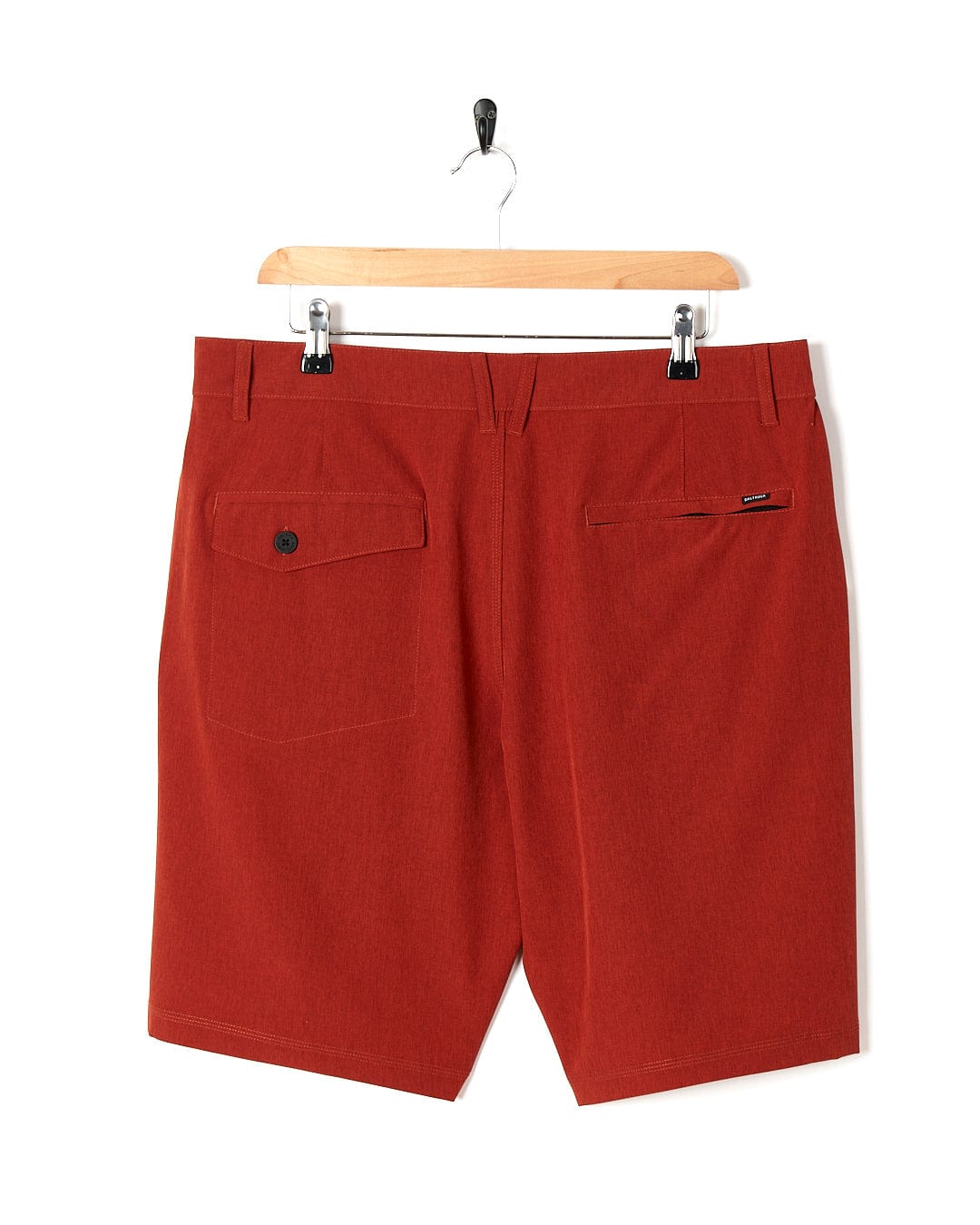 A pair of Amphibian II - Mens Boardshort - Red shorts hanging on a hanger by Saltrock.