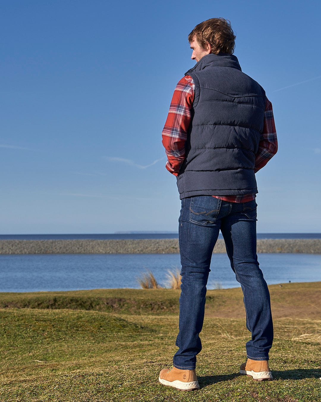 A man standing on a field looking at the Bardsey - Mens Gilet - Blue by Saltrock.