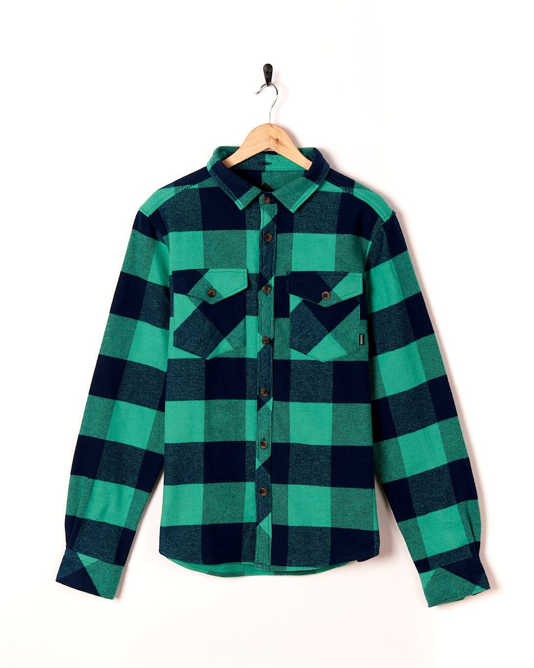 A Saltrock Beale - Mens Heavy Weight Hooded Shirt - Dark Green flannel shirt hanging on a wall.