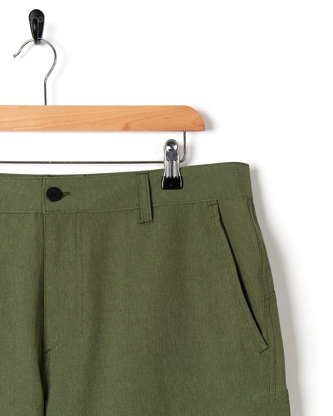 A pair of essential men's green Saltrock Cargo Amphibian II - Mens Boardshort - Dark Green shorts hanging on a hanger.