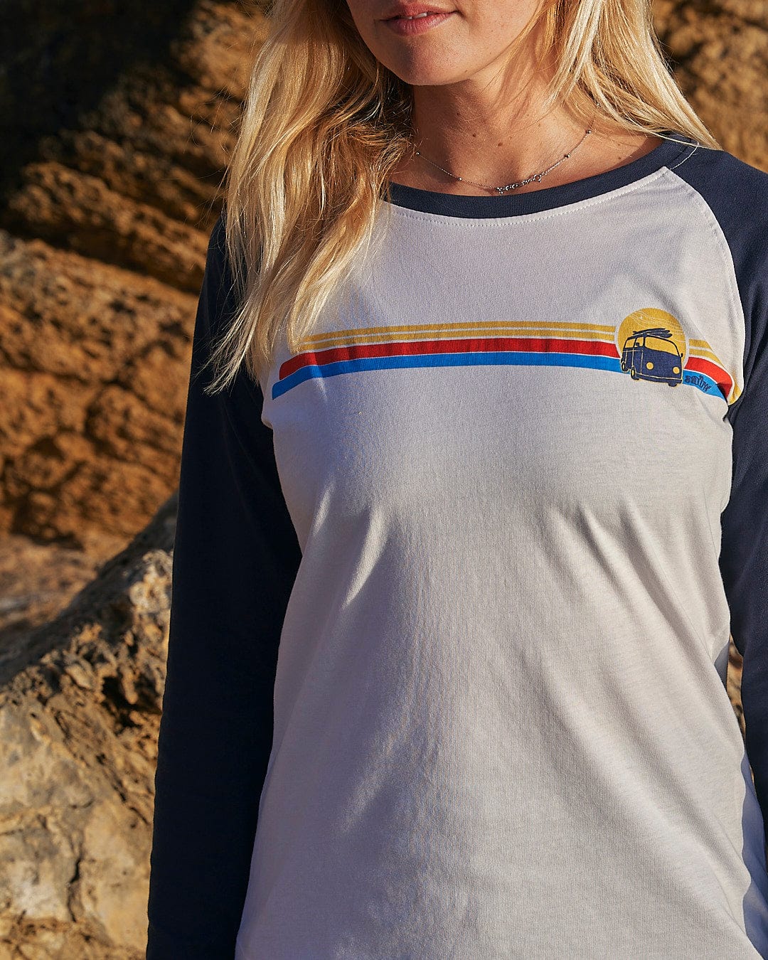 A woman wearing a Saltrock Celeste Stripe - Womens Long Sleeve Raglan T-Shirt in front of a rock.