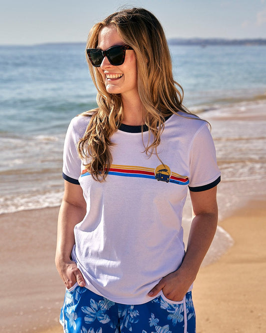 Description: A woman wearing a Saltrock Celeste Stripe - Womens Ringer Tee - White and blue shorts standing on the beach.