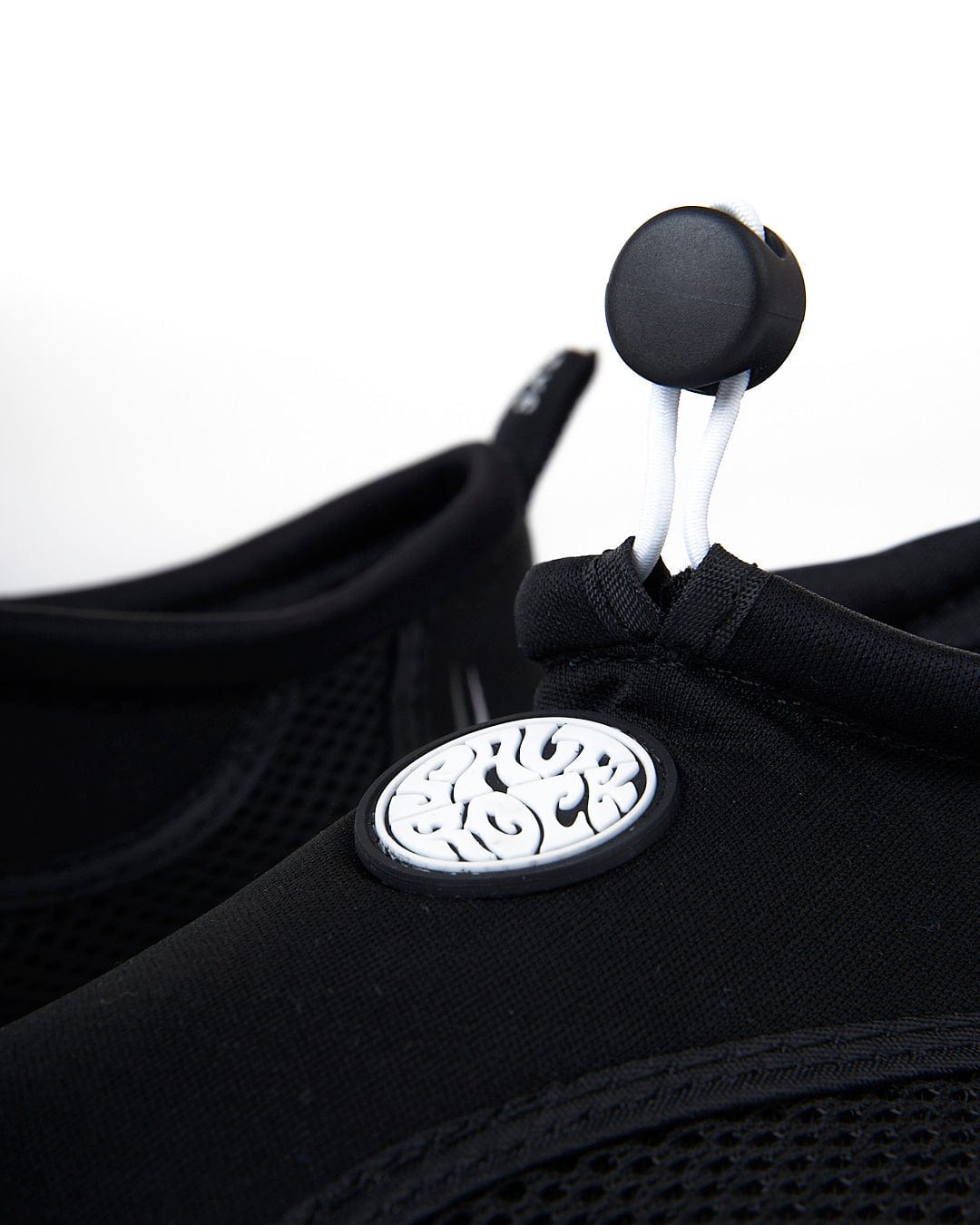 Close-up view of a black Saltrock Core Aqua Shoe fabric with a zipper and a distinctive round logo on a pull tab.