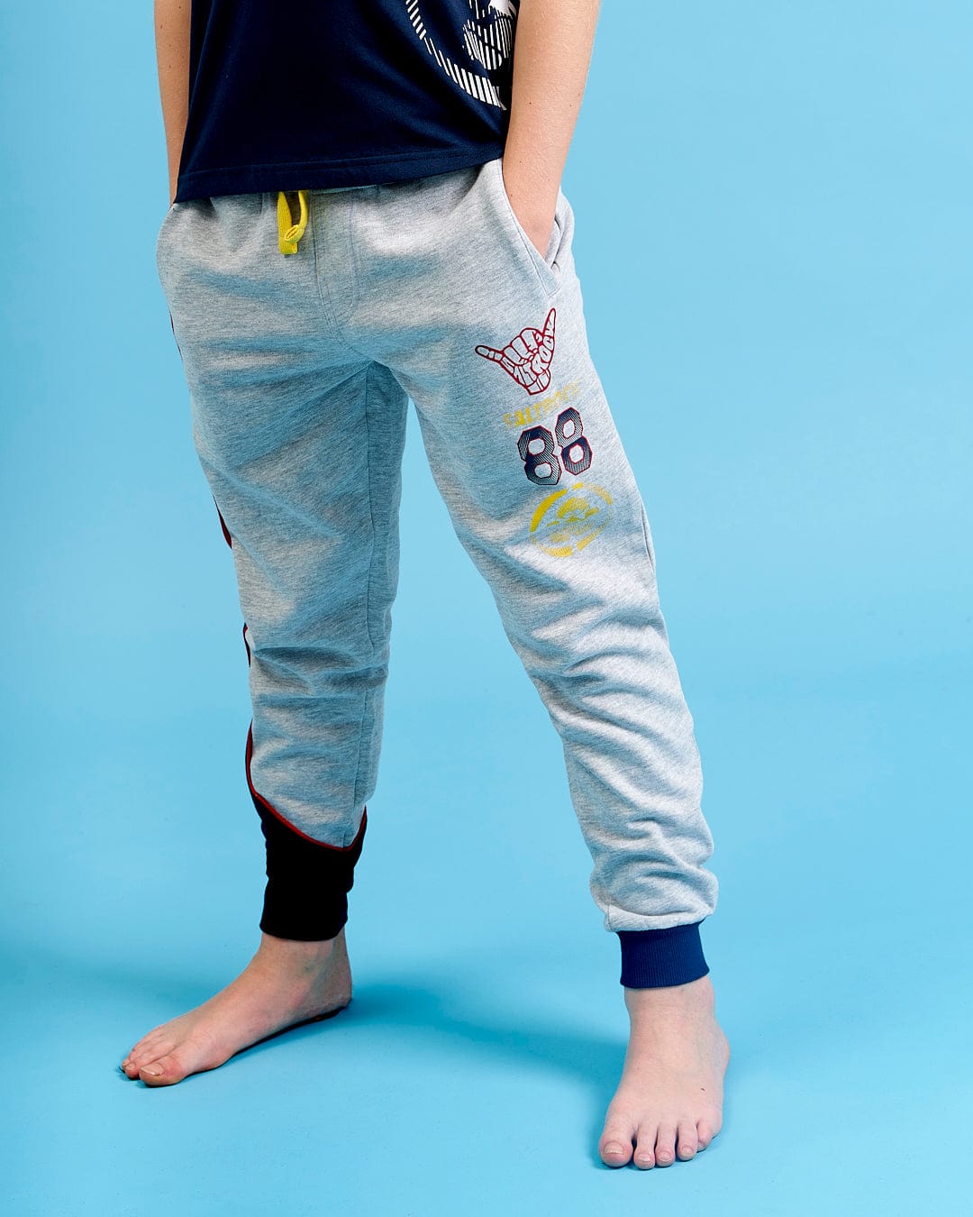 A young boy wearing Saltrock Curby - Kids Jogger - Grey joggers and a black shirt.