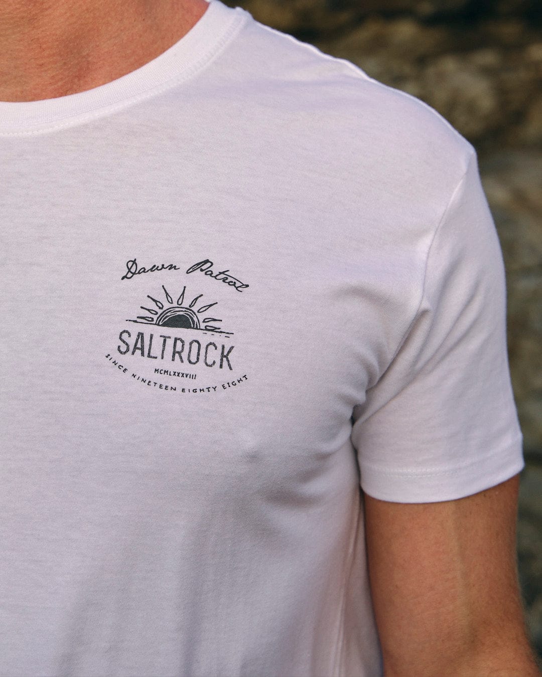 A man wearing a white t-shirt that says Saltrock's Dawn Patrol - Mens Short Sleeve T-Shirt - White.