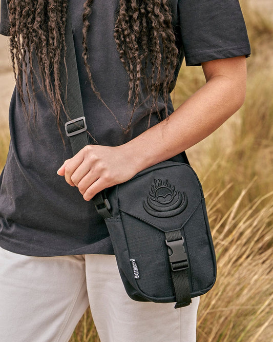 Person wearing a Saltrock Festival black shoulder bag with an adjustable strap and a buckle fastening.