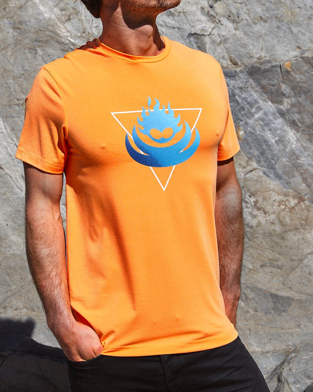 A man wearing a Saltrock Flame Tri - Mens Recycled Short Sleeve T-Shirt - Light Orange with a blue triangle on it.