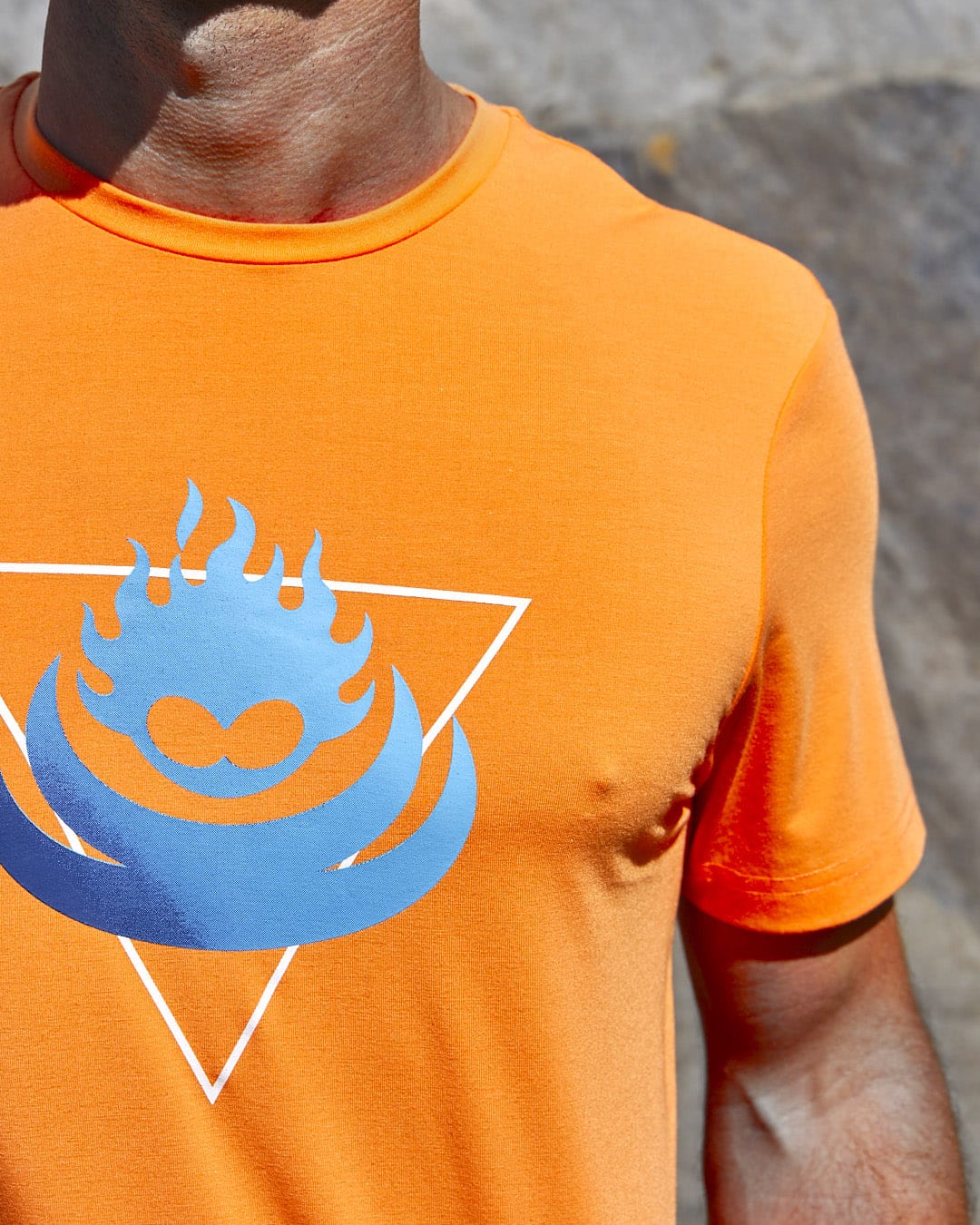 A man wearing a Saltrock Flame Tri - Mens Recycled Short Sleeve T-Shirt - Light Orange with a blue heart on it.