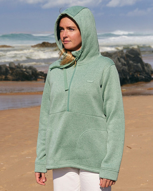 A woman in a Saltrock Galaksea - Womens 1/4 Zip Fleece - Light Green hoodie standing on a beach.
