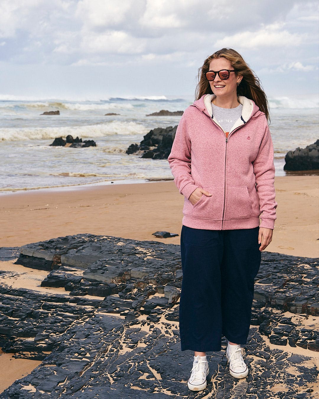 A woman enjoying an adventure on the beach, clad in a comfortable Saltrock Galak - Womens Fur Lined Hoody - Pink.