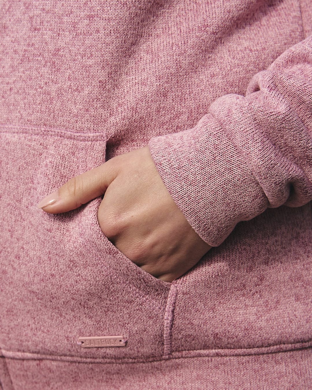 A close up of a woman wearing a Saltrock Galak - Womens Fur Lined Hoody in pink, exuding comfort and ready for adventure.