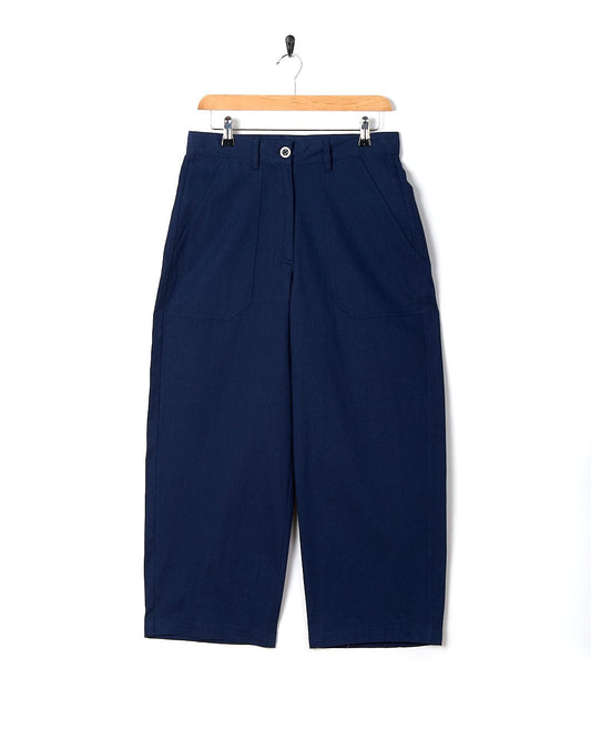 A pair of Hilda - Womens Canvas Trouser - Dark Blue trousers by Saltrock hanging on a hanger.