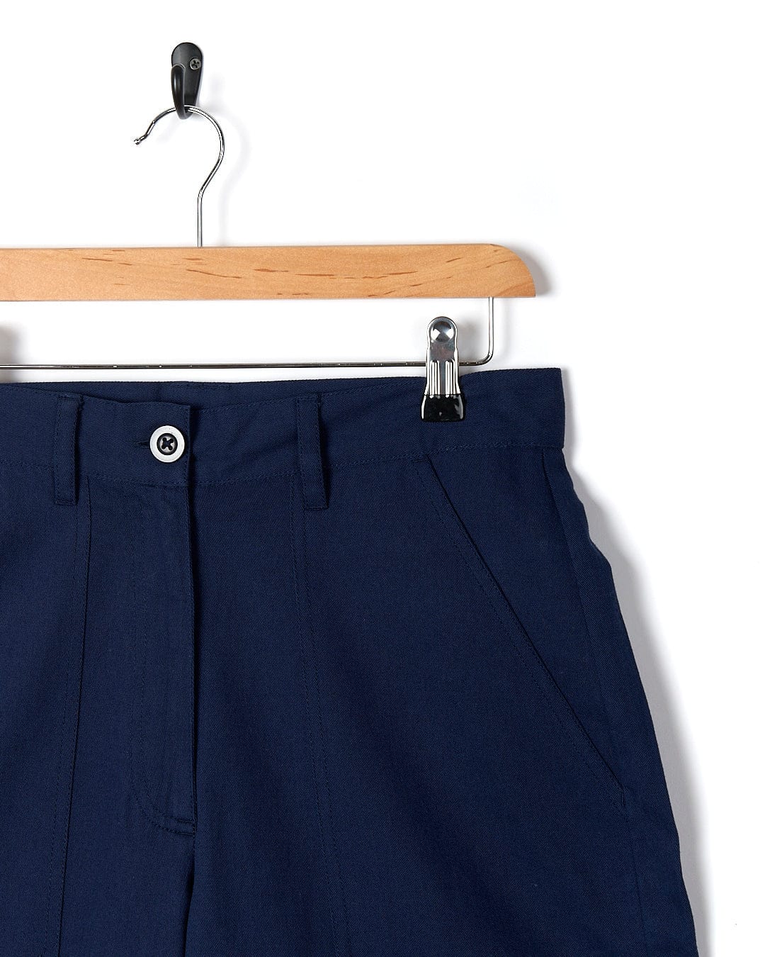 A pair of Hilda - Womens Canvas Trouser - Dark Blue shorts hanging on a hanger. Brand: Saltrock.