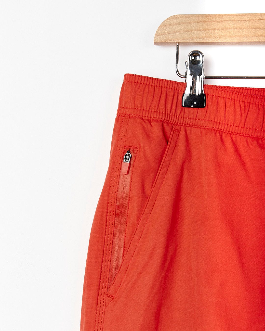 A pair of Saltrock - Lee Mens Sueded Volley Swimshort - Red hanging on a hanger.