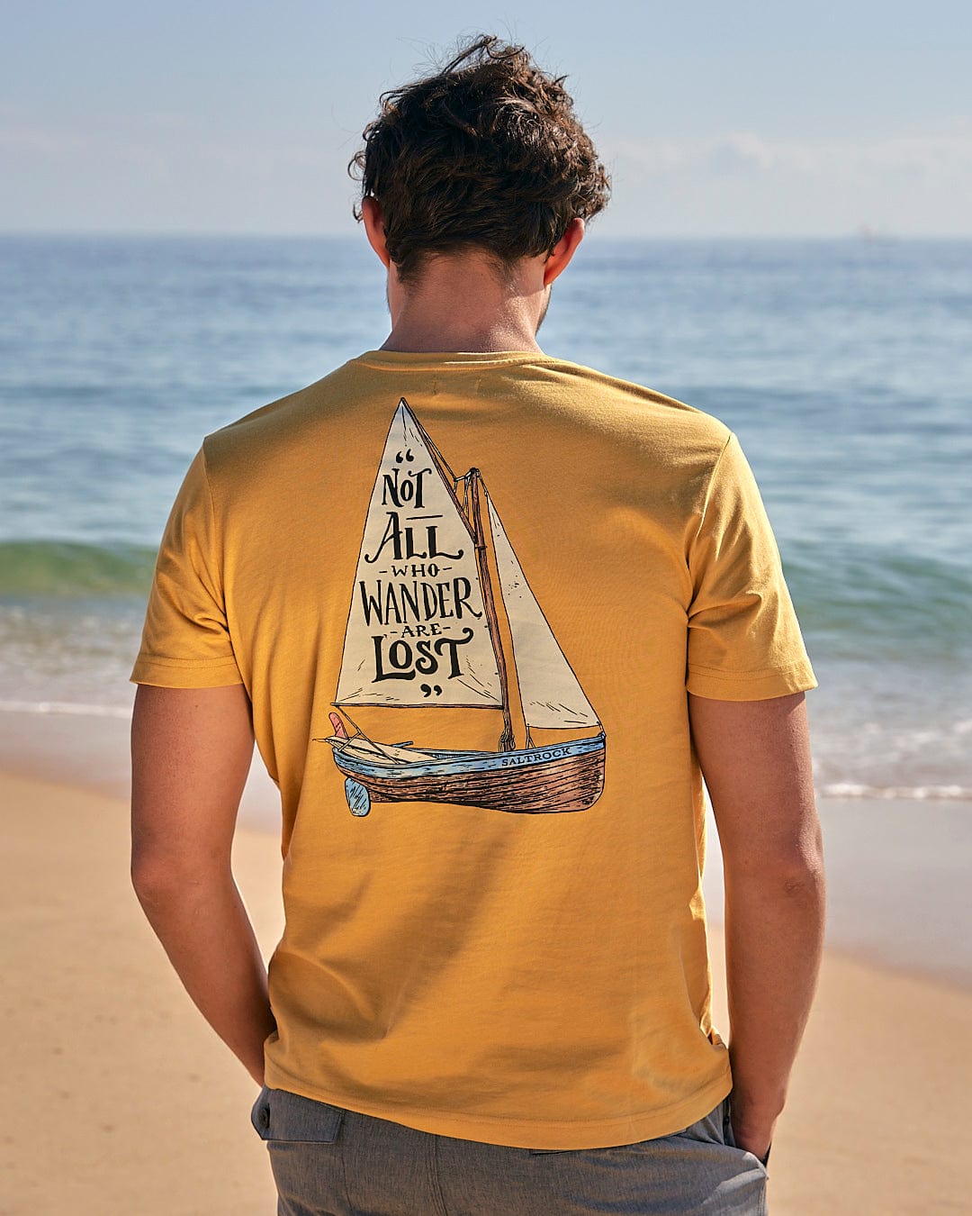 The back of a man wearing a Saltrock Lost Ships - Mens Short Sleeve T-Shirt - Yellow with a sailboat on it.
