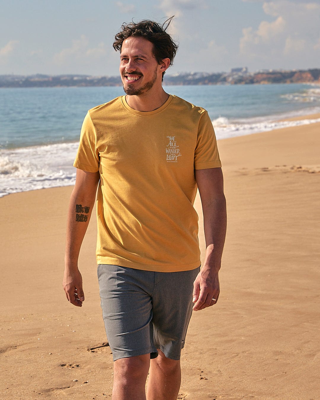 A man walking on the beach wearing a Lost Ships - Mens Short Sleeve T-Shirt in Yellow from Saltrock.