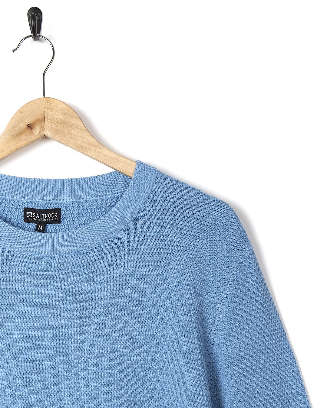 A Saltrock - Moss Mens Washed Knitted Crew - Light Blue sweater hanging on a hanger.
