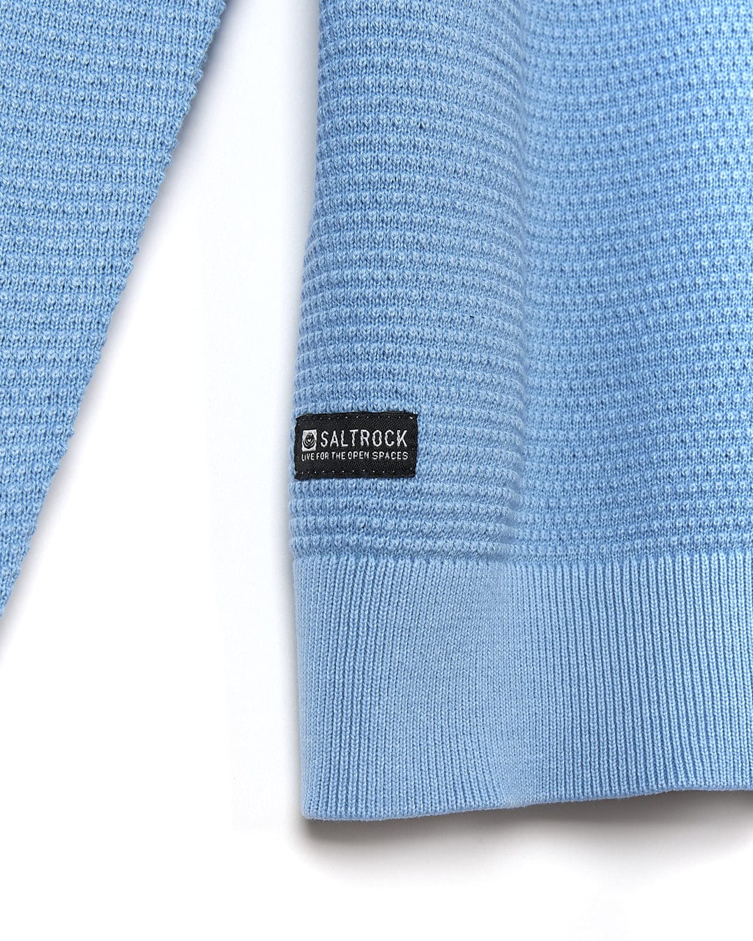 A close up of a Saltrock Moss - Mens Washed Knitted Crew - Light Blue sweater with a logo on it.
