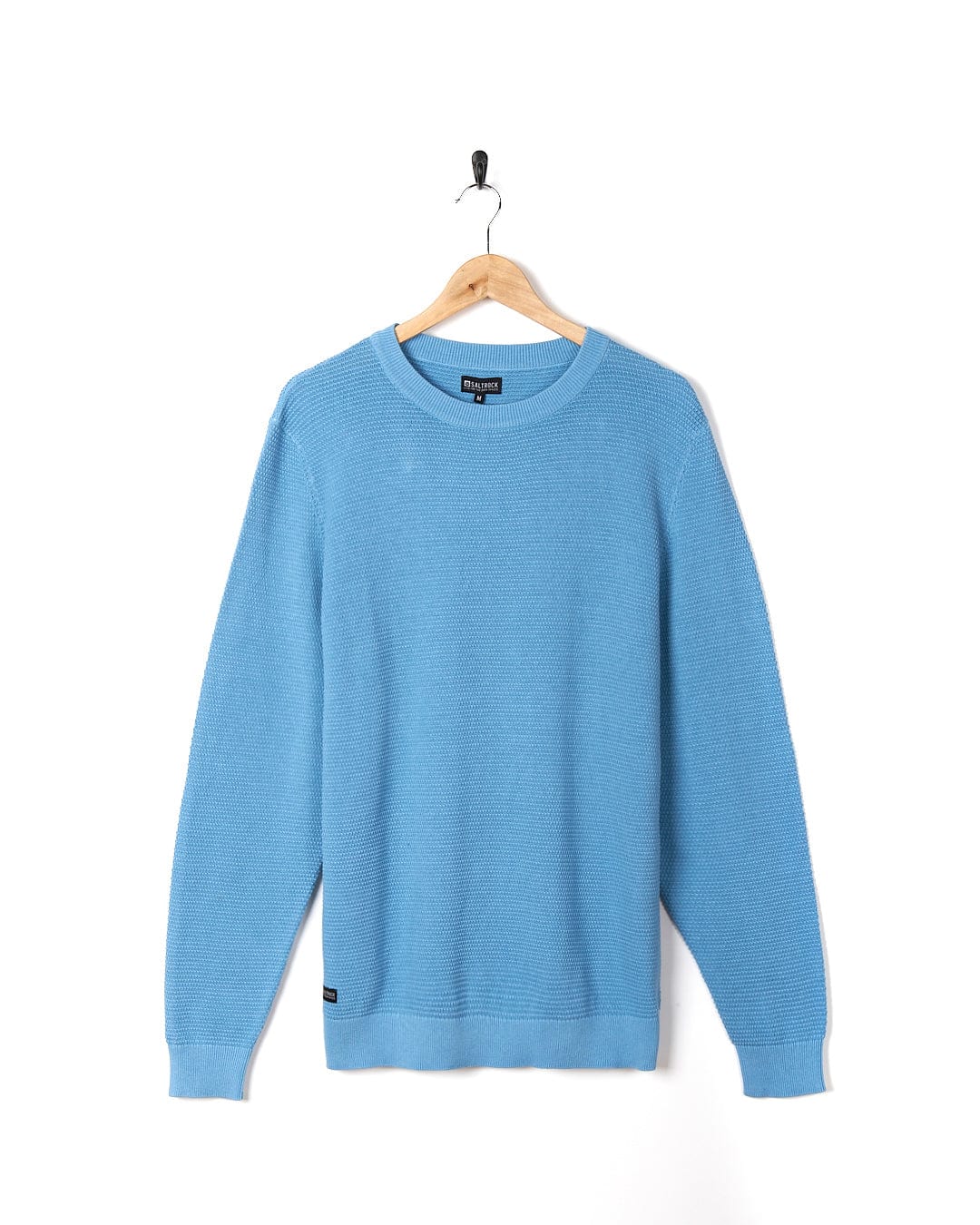 A Saltrock - Mens Washed Knitted Crew - Light Blue sweater hanging on a hanger.