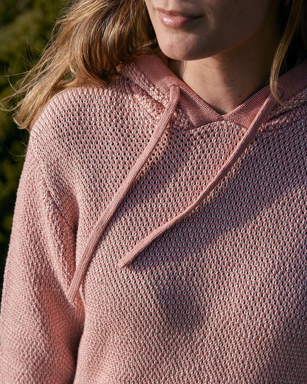 A woman wearing a Saltrock Poppy - Womens Knitted Pop Hoodie - Mid Pink sweater.