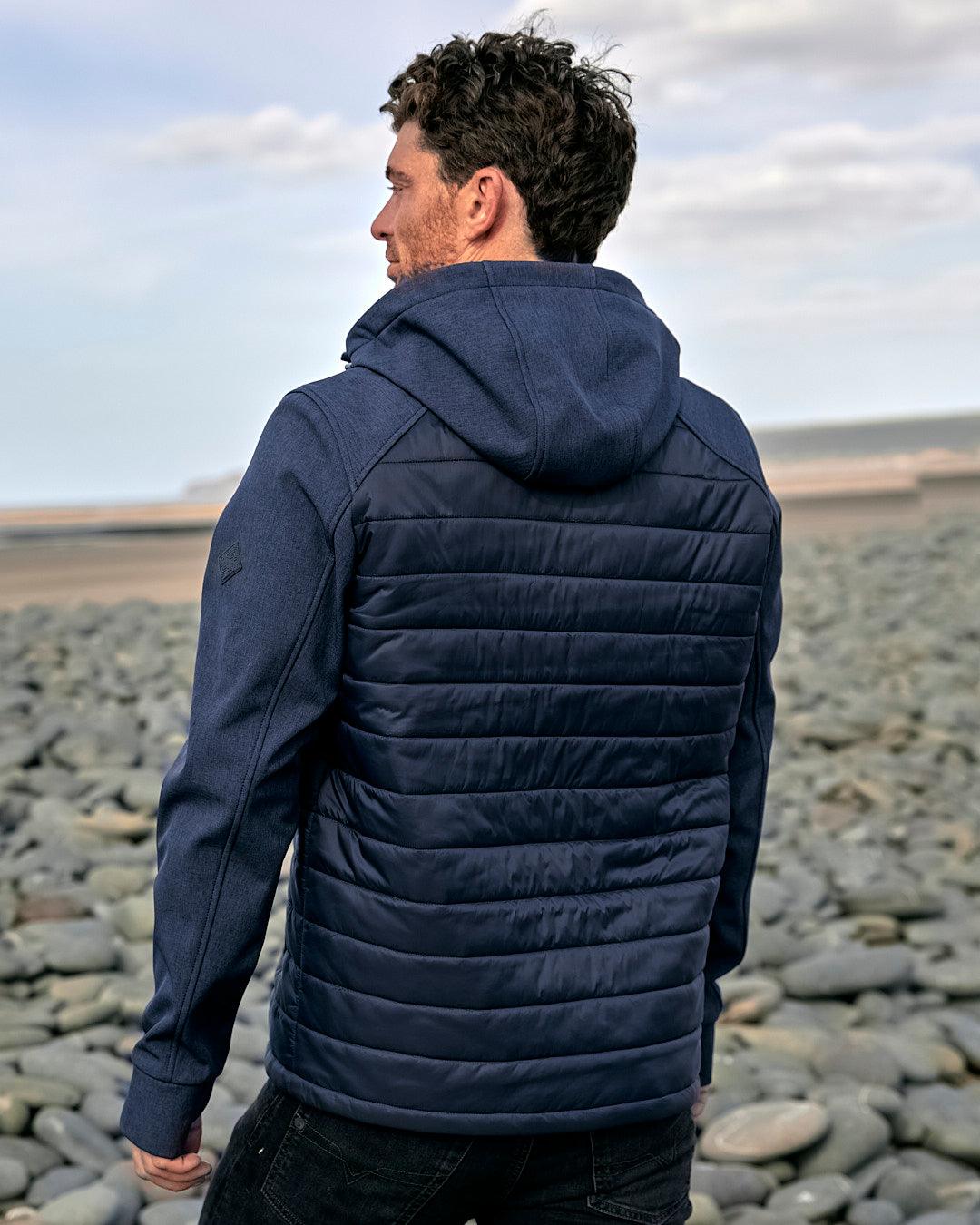 The back of a man wearing a Saltrock Purbeck Padded Jacket - Dark Blue, perfect for outdoor adventures.