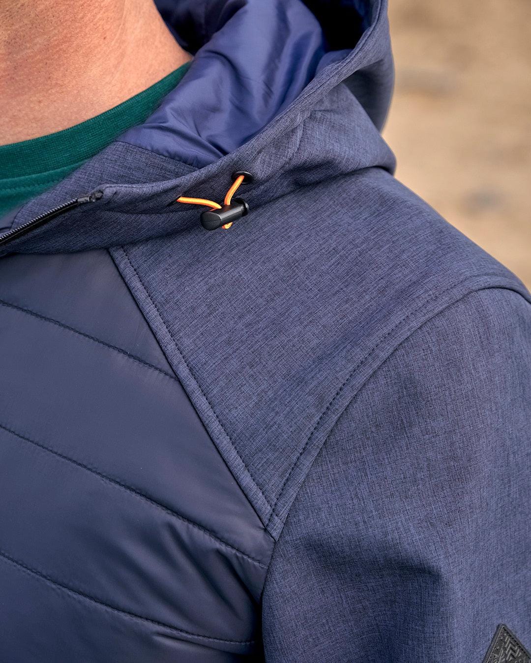 A close up of a man wearing the Saltrock Purbeck Padded Jacket - Dark Blue.