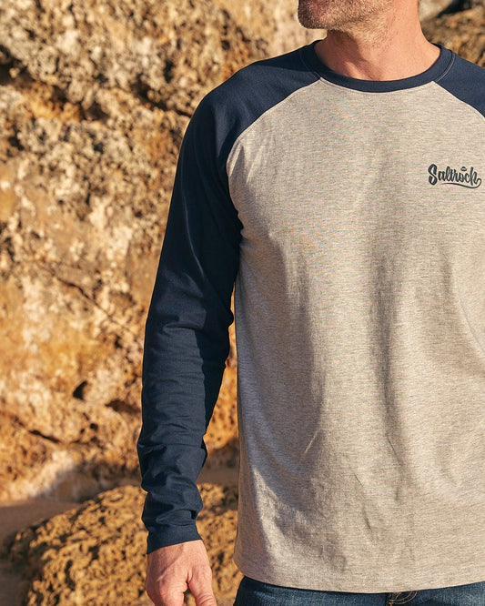 A man wearing a grey and navy Saltrock Speed - Mens Long Sleeve Raglan T-Shirt - Blue.