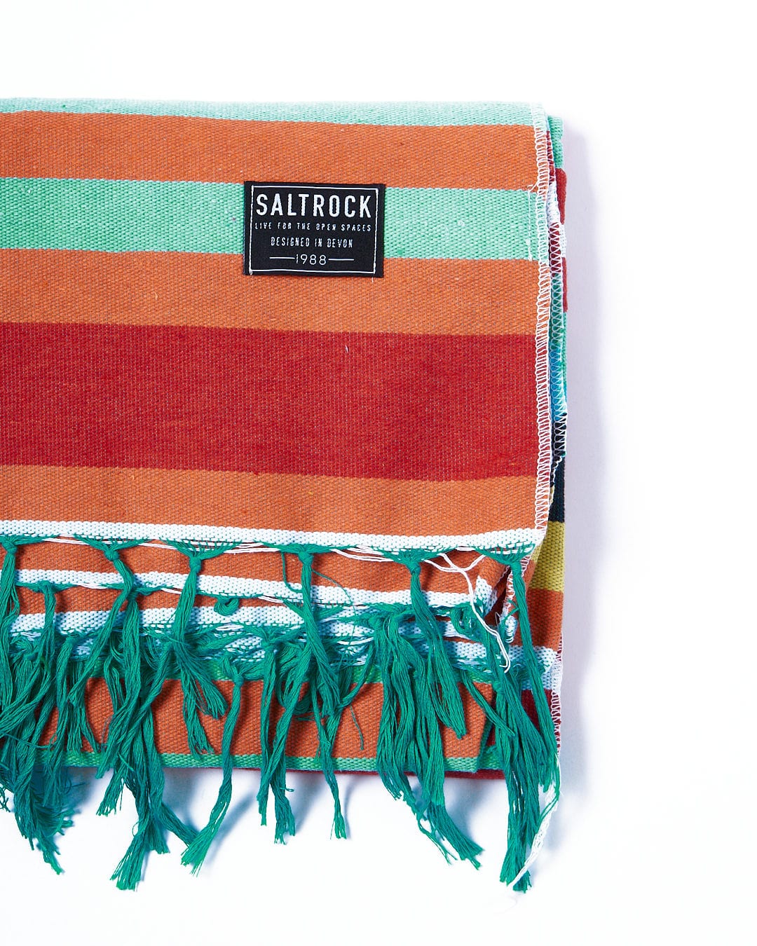 A colorful striped Recycled Picnic Blanket - Multi with fringes on it by Saltrock.
