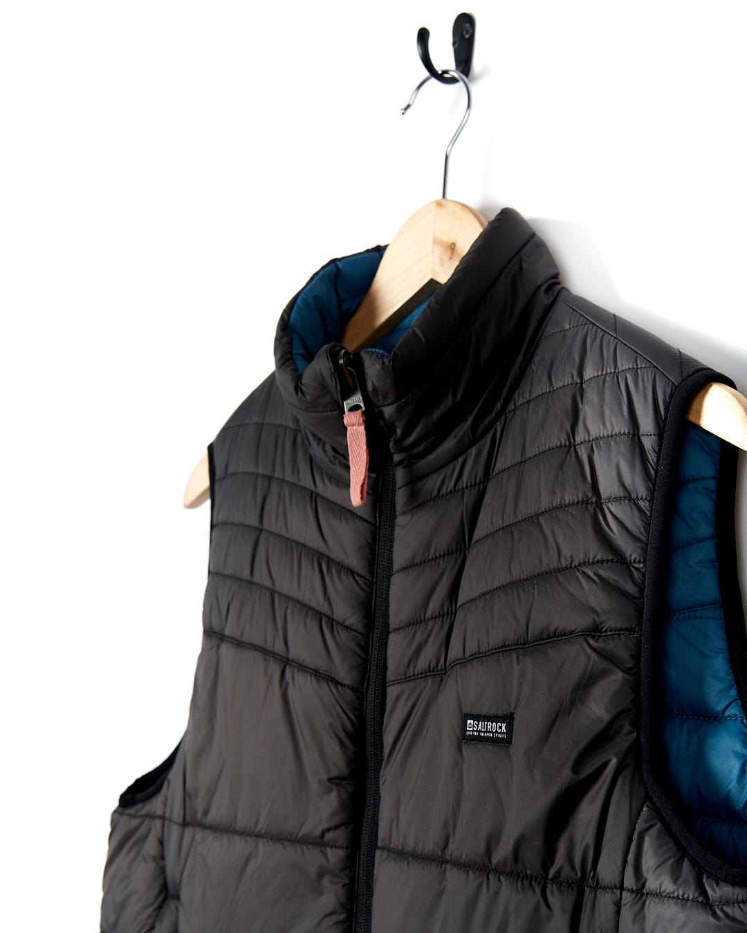 A Saltrock - Womens Ridleys Reversible Gilet in black and blue, ideal as a travel buddy due to its water-resistant features, hanging on a hanger.