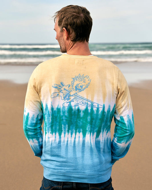 A man standing on the beach wearing a Saltrock Running Man - Mens Tie Dye Crew Sweat - Light Yellow/Blue.