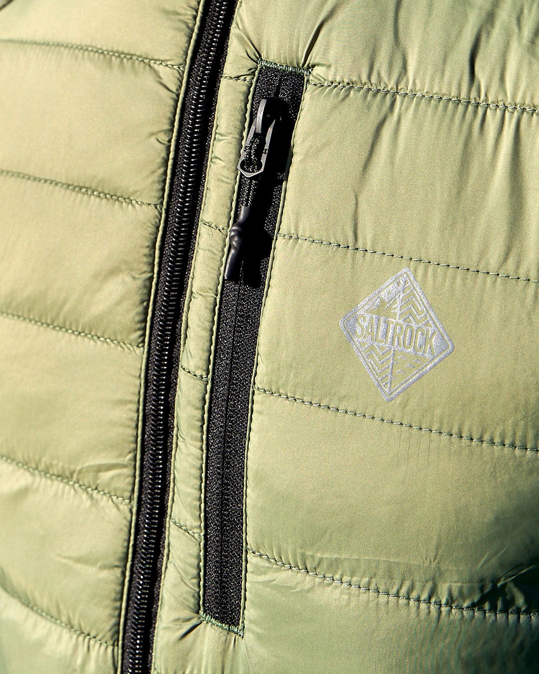A close up of the zipper of a Saltrock Scott - Mens Reversible Gilet - Dark Green/Black puffy jacket.