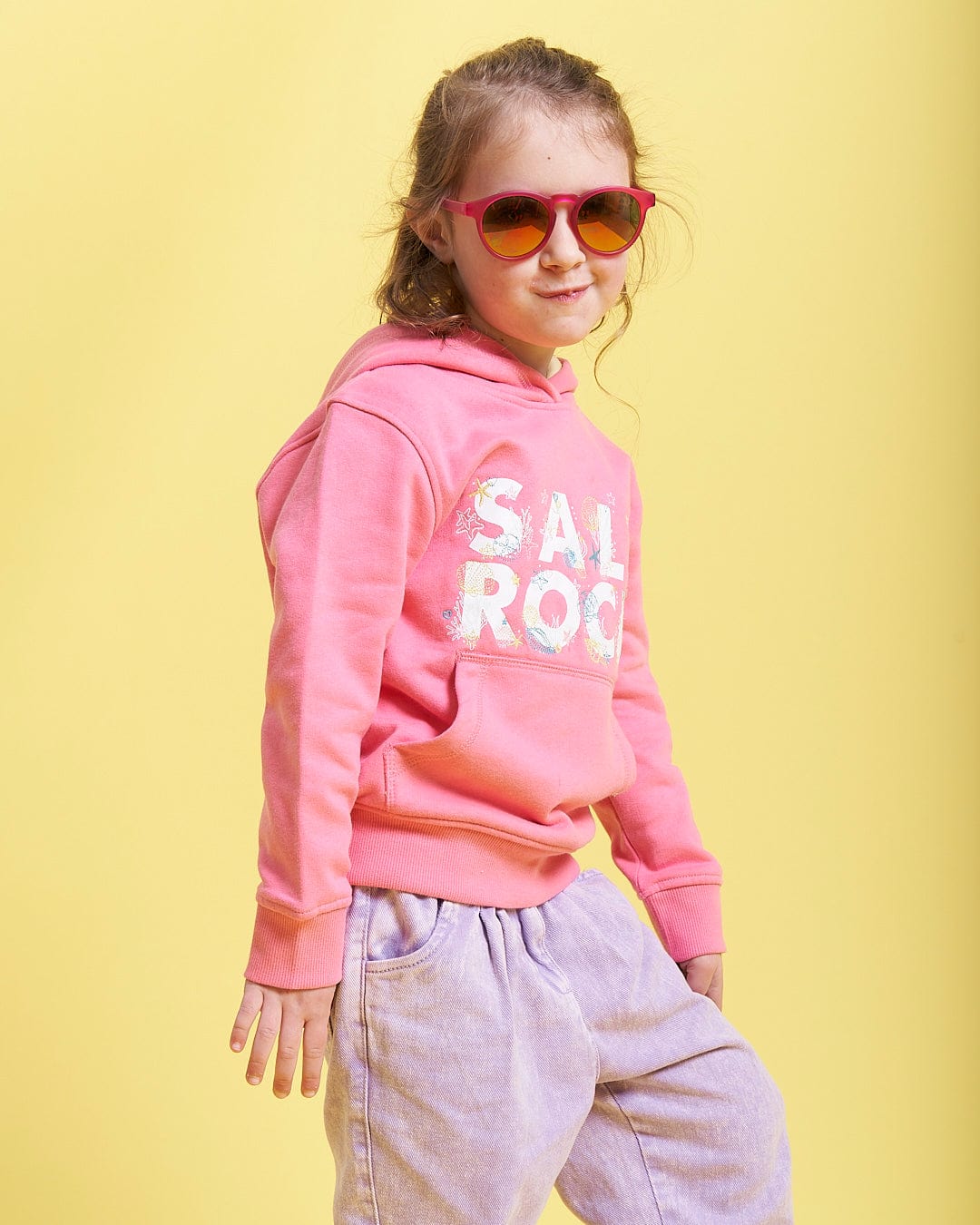A little girl wearing Saltrock Seabed - Kids Pop Hoodie - Pink sunglasses and a pink sweatshirt.