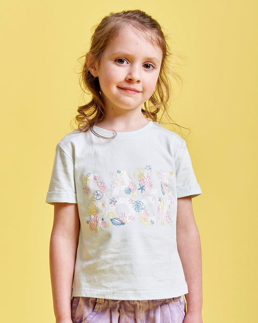 A girl wearing a Saltrock Seabed - Kids Short Sleeve T-Shirt in Light Blue is posing for a picture.
