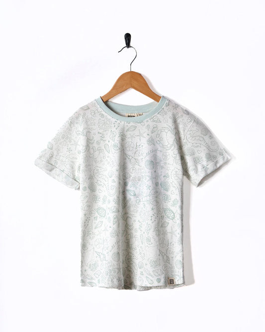 A Seashore - Kids All Over Print Short Sleeve T-Shirt - White hanging on a wooden hanger. Brand Name: Saltrock.